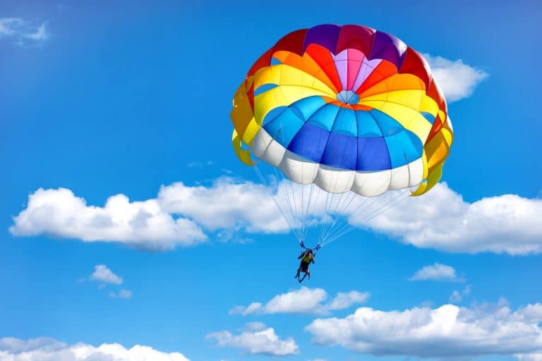 Parachute ascensionnel coloré dans le ciel bleu avec nuages.