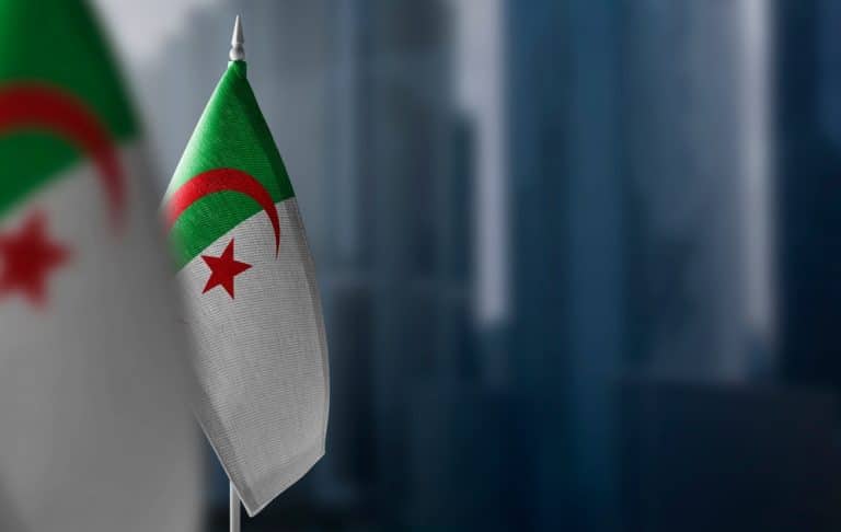 drapeaux de l'Algérie devant des bâtiments flous en arrière-plan