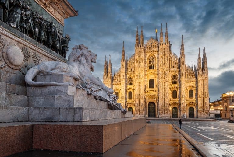 vue du Duomo de Milan au crépuscule avec sculpture de lion en premier plan.