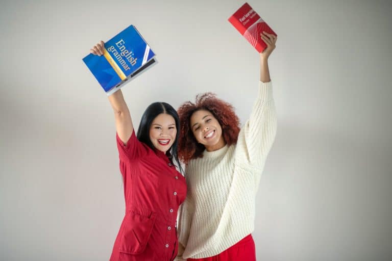 deux femmes souriantes tenant des livres d'anglais en l'air.