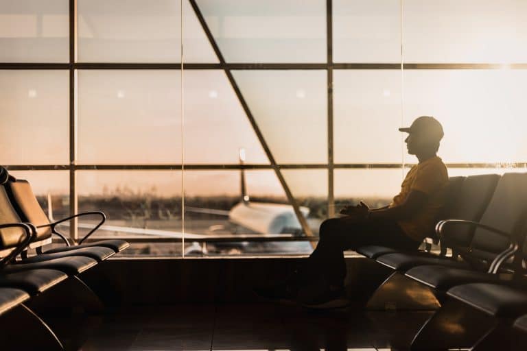 homme assis à l'aéroport avec vue sur le tarmac au coucher du soleil