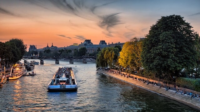 croisière sur la Seine à Paris au coucher de soleil avec des touristes et des arbres le long des berges