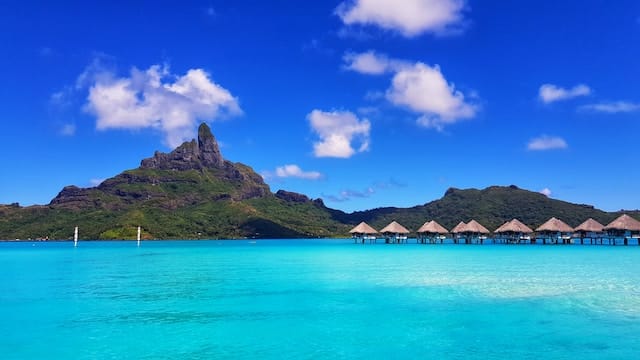vue pittoresque d'île tropicale avec montagne, bungalows sur l'eau et ciel bleu
