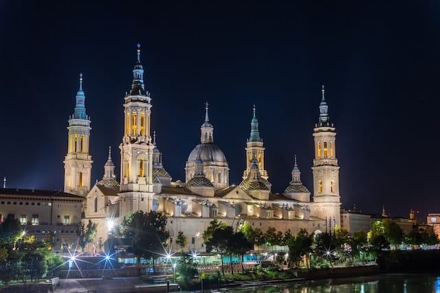 vue nocturne de la basilique-cathédrale de notre-dame du pilier à saragosse, espagne, illuminée avec réflexion dans l'eau.