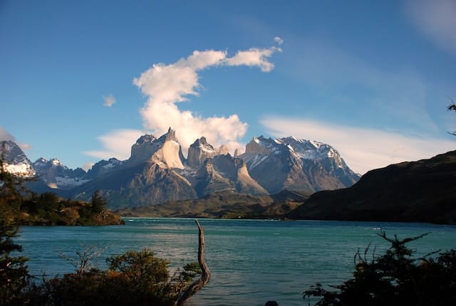 Paysage du parc national Torres del Paine avec montagnes escarpées, lac turquoise et ciel nuageux.