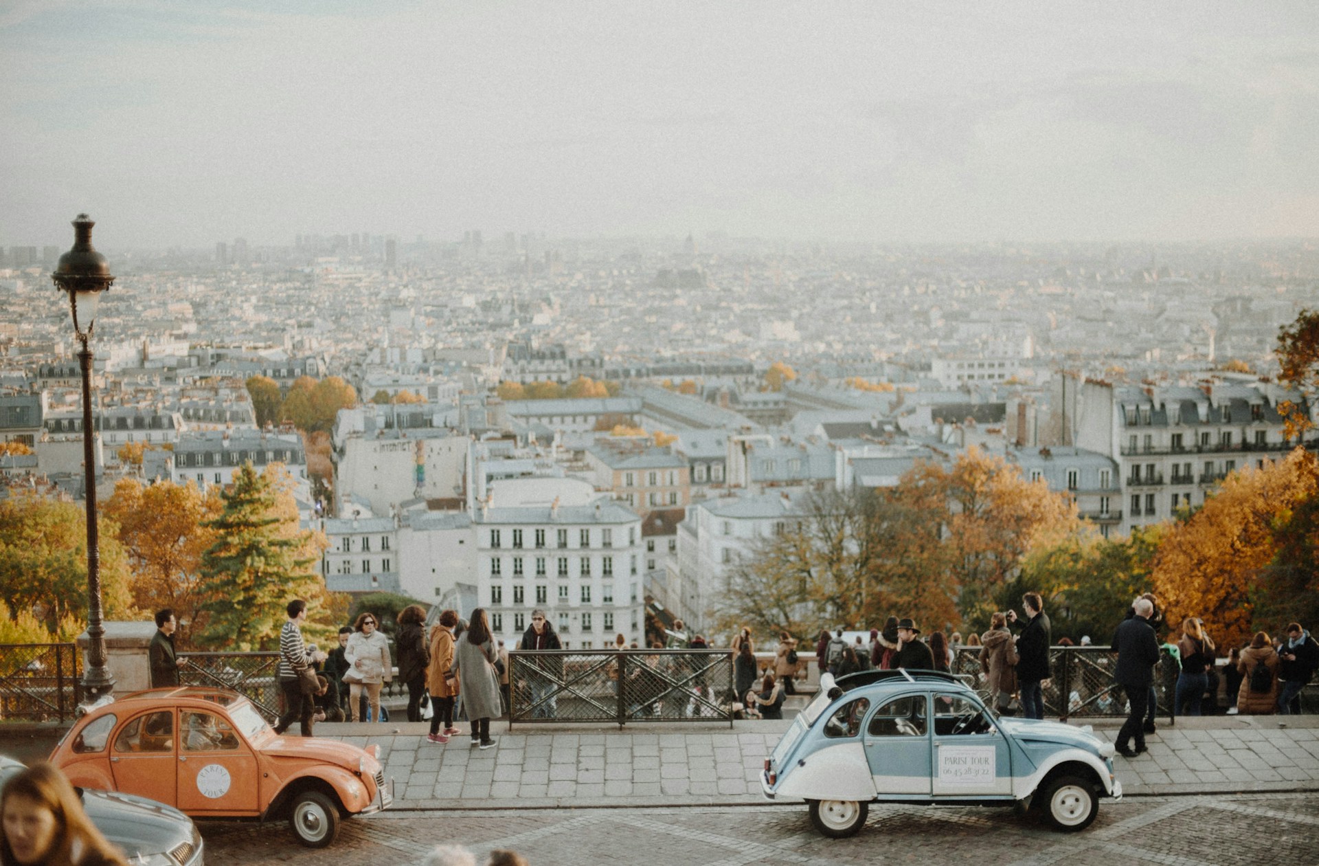 deux voitures vintage garées devant la skyline de paris avec touristes