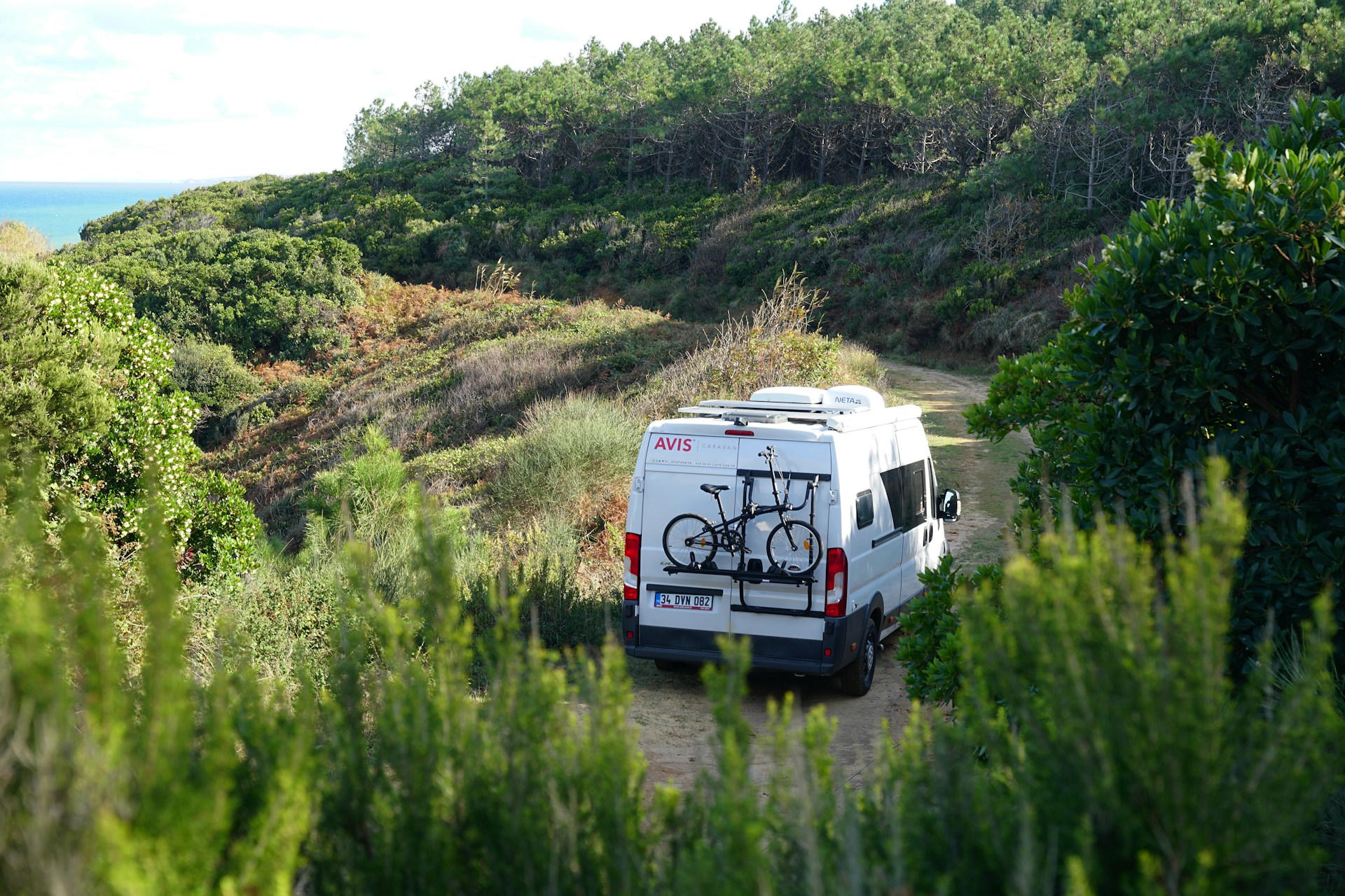 fourgon aménagé blanc avec vélo sur porte-bagages en montagne méditerranéenne