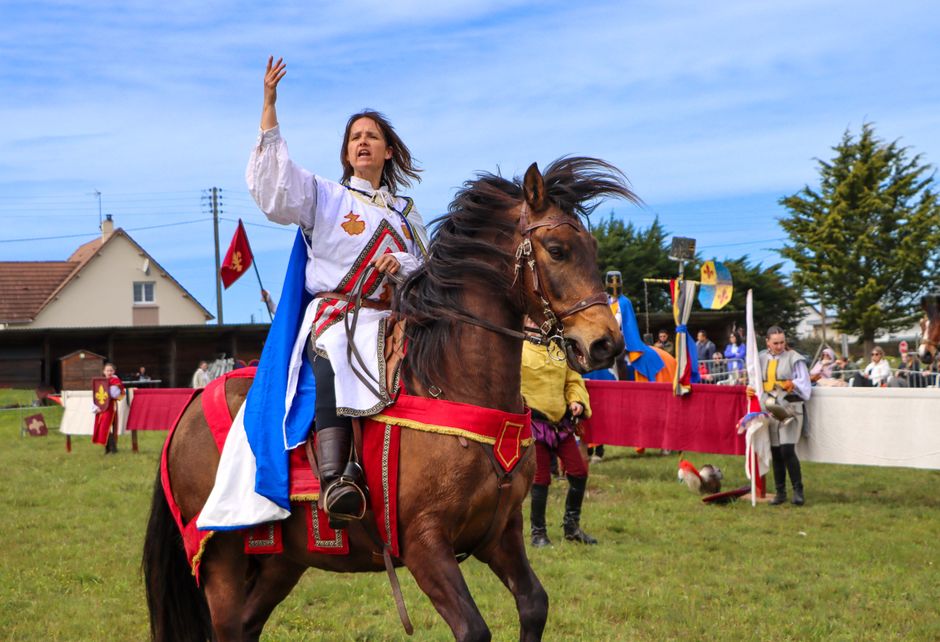 A woman in medieval costume performs on horseback at a festival in Bréhal, France.