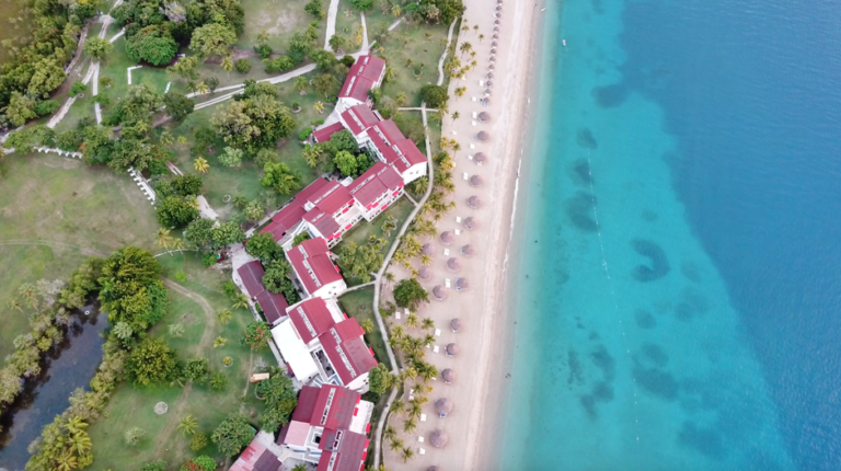 Drone shot of a beachfront resort in Haiti with turquoise waters and lush greenery.