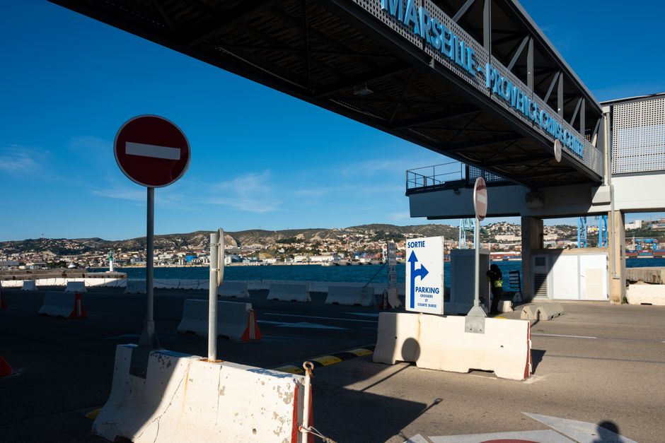 View of traffic signs and terminal bridge at Marseille Provence cruise port under blue sky.