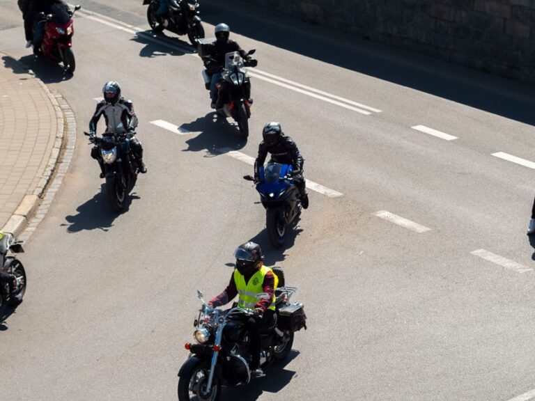 Aerial view of motorcyclists riding through a street in Wrocław, Poland on a sunny day.
