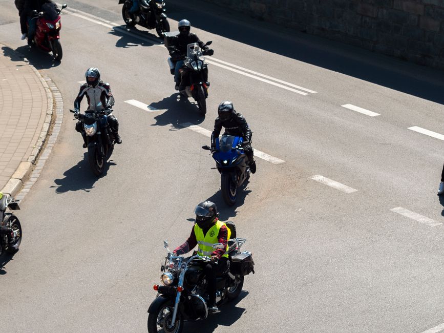 Aerial view of motorcyclists riding through a street in Wrocław, Poland on a sunny day.