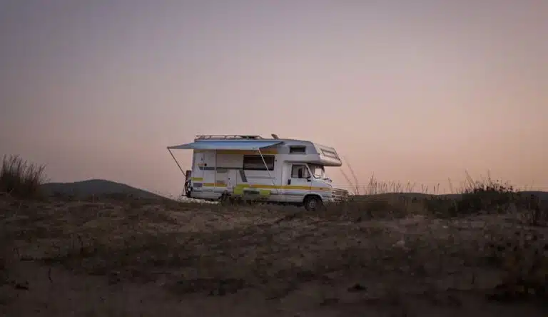 A serene view of an RV parked amidst nature during sunset, capturing a travel adventure.