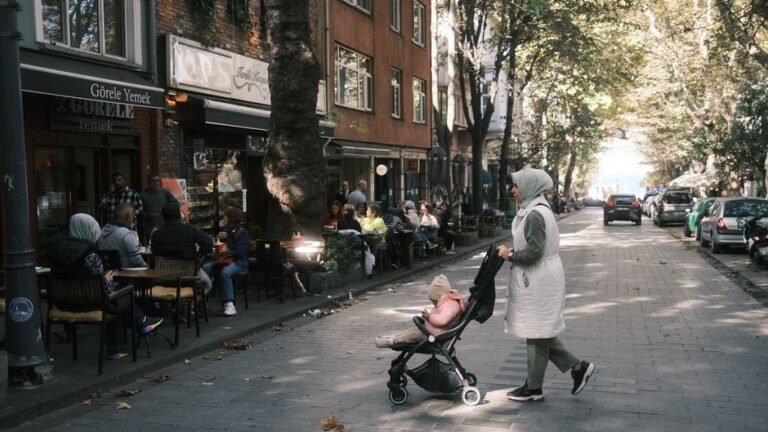Urban street in İstanbul featuring pedestrians and outdoor cafes under autumn sunlight.