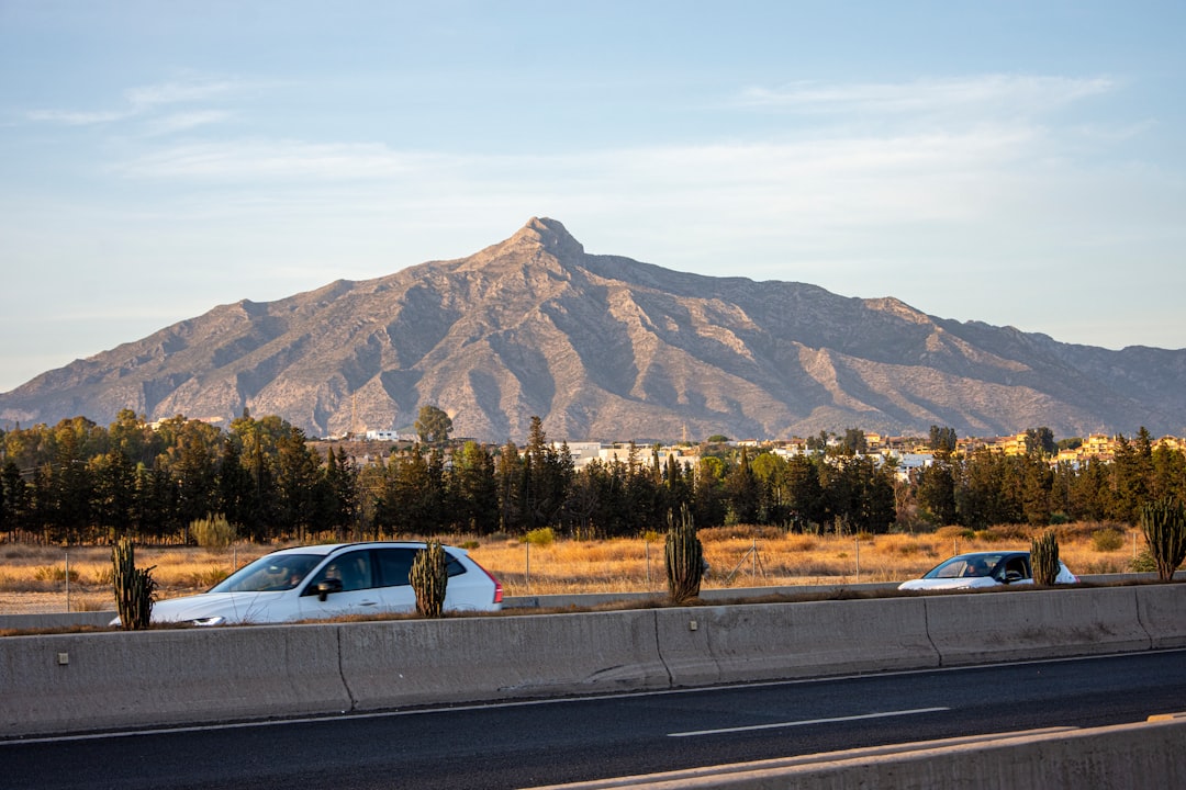 Cars on a highway with a large mountain backdrop.